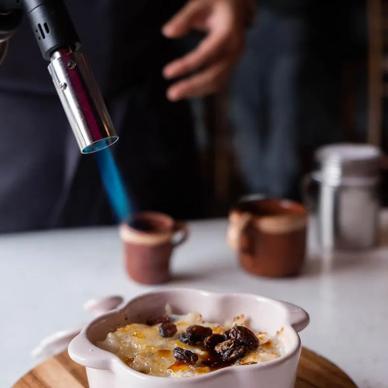 A pastry chef torching the sugar crust on a dessert at the pass