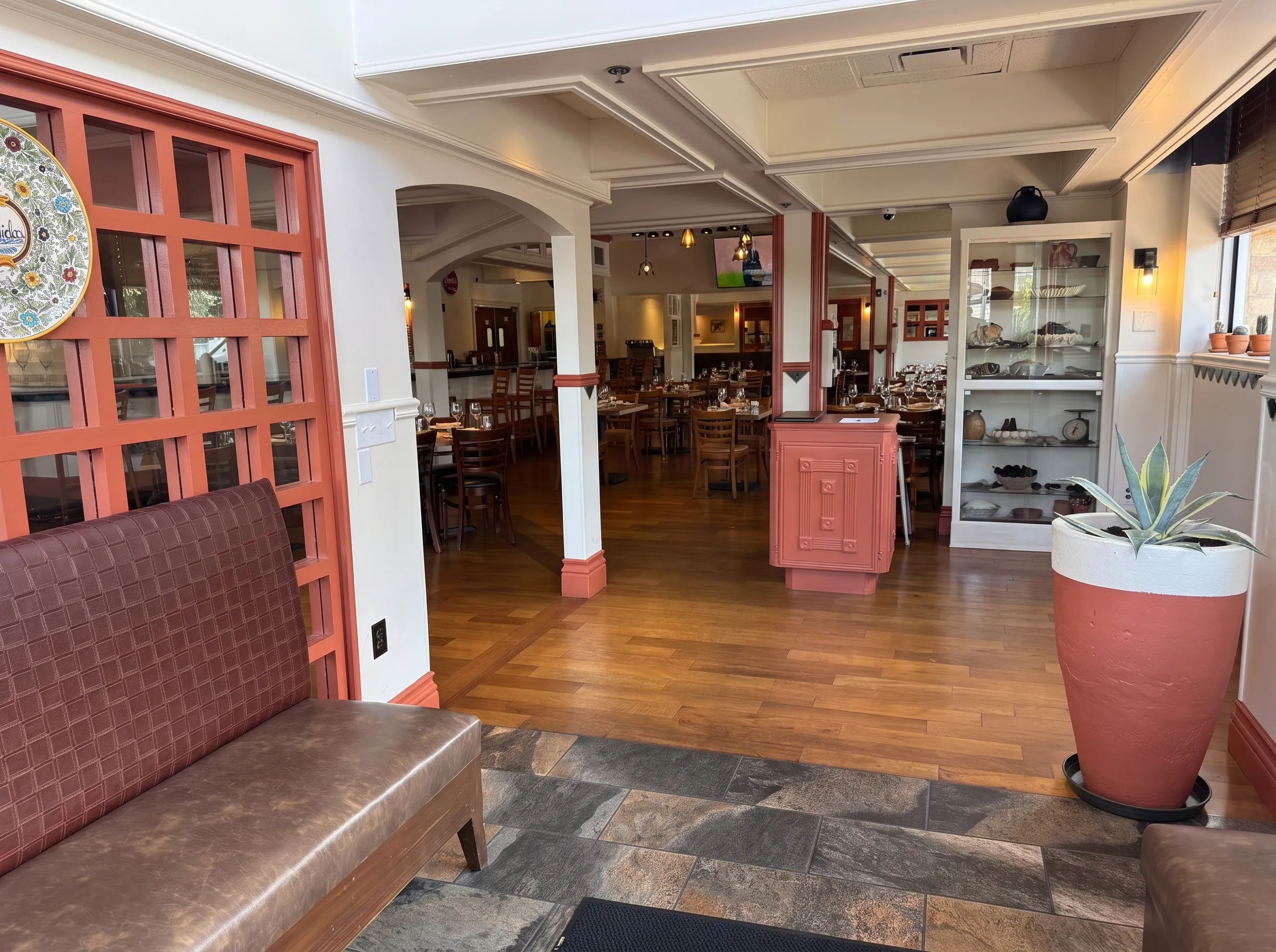 The entry at Panfila with a terracotta lattice screen and a cabinet of folk-art pieces