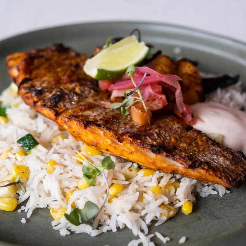 Grilled fish fillet over rice with corn and pickled onion