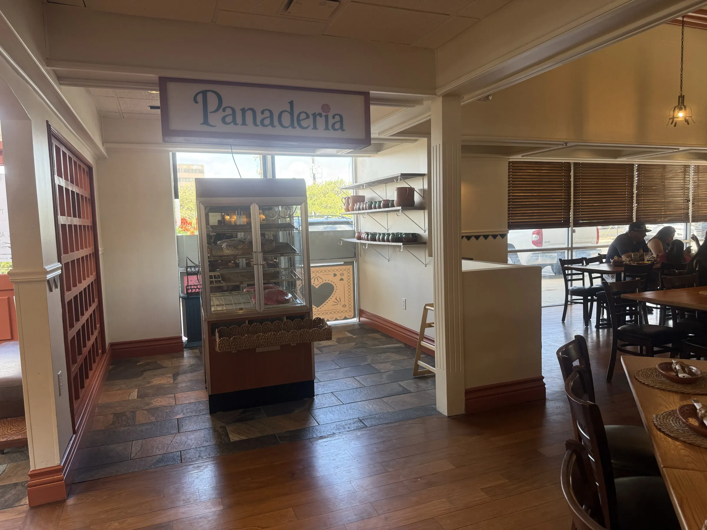 The Panfila panadería corner with its hanging sign, pastry case, wood tables and terracotta trim