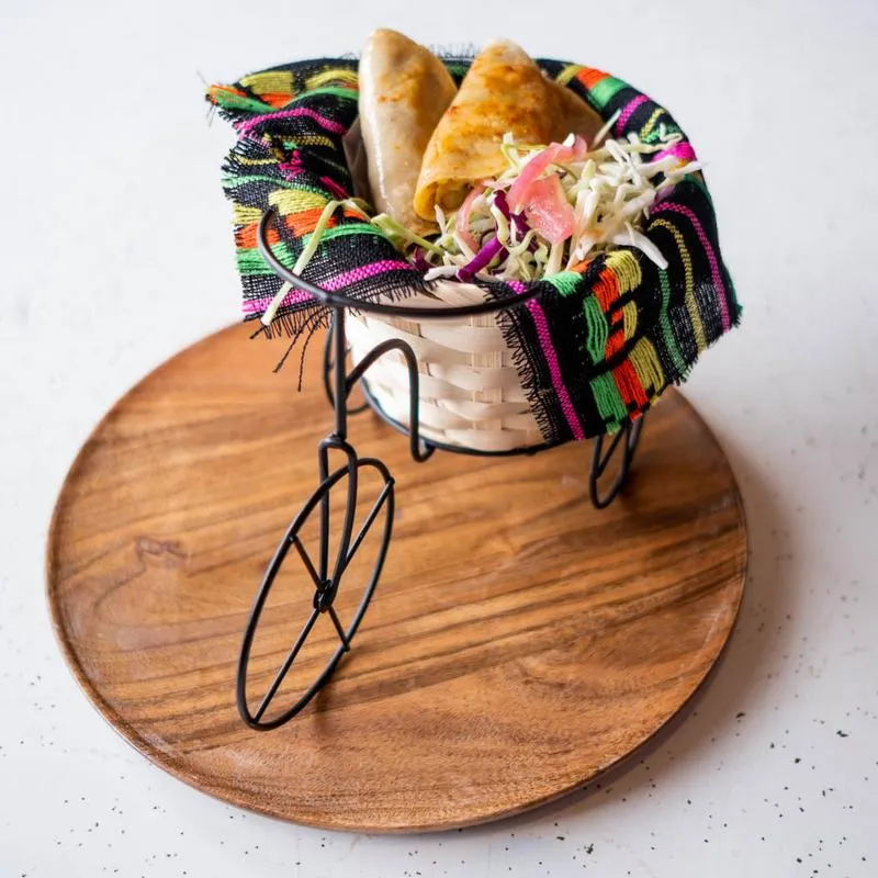 Warm tortillas in an embroidered cloth basket beside a wooden board